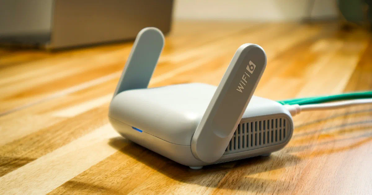 Small gray Wi-Fi 6 router with two flip-up antennas on a wooden table