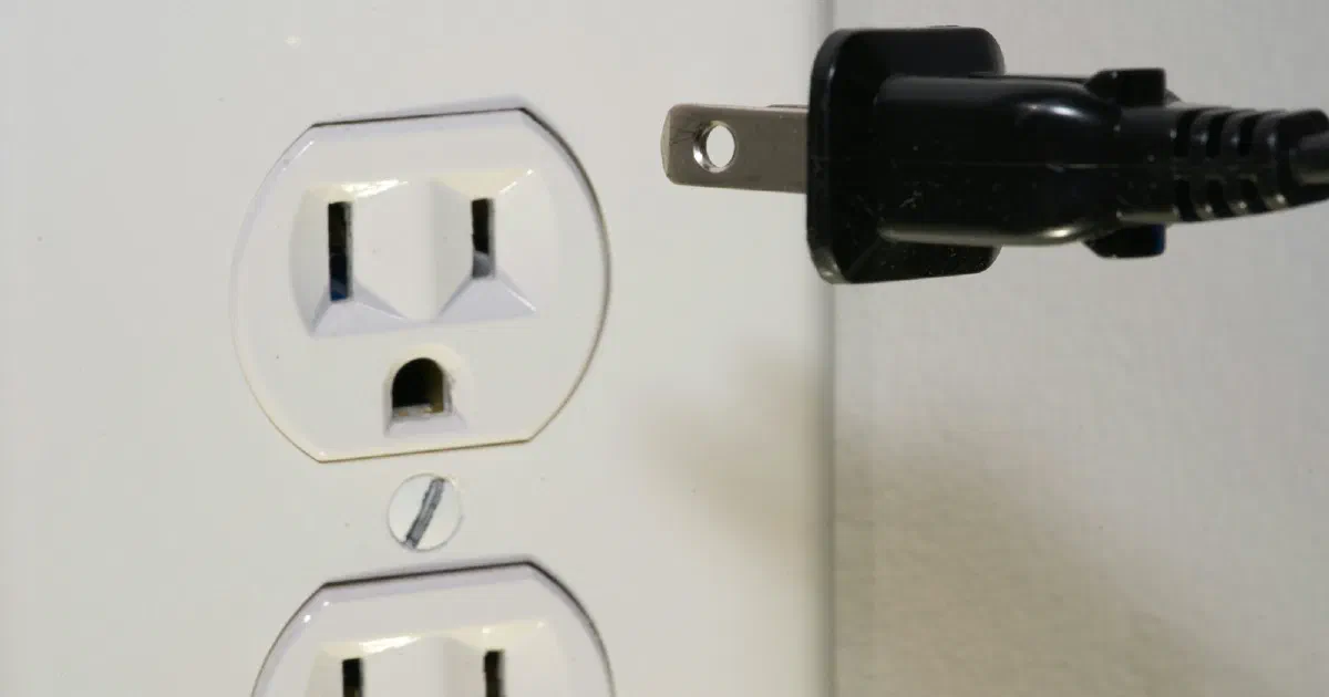 Plug being inserted into a US electrical wall outlet