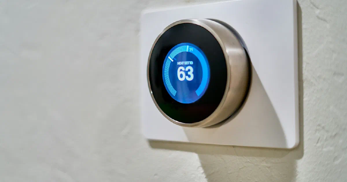 Round smart thermostat on a white wall showing 63 degrees