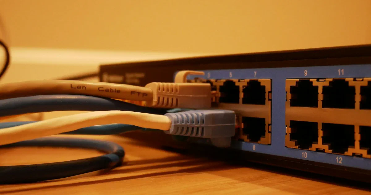 Ethernet cables plugged into the ports of a network switch on a wooden desk