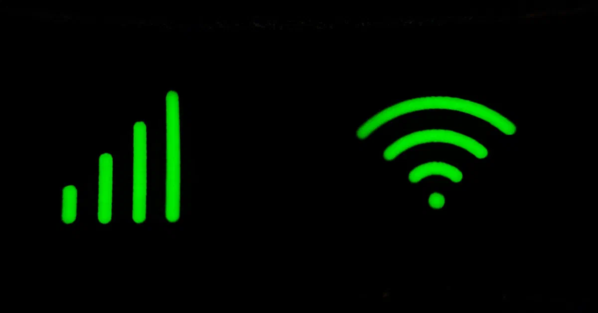 Glowing green signal-strength bars and a Wi-Fi symbol on the front of a dark router