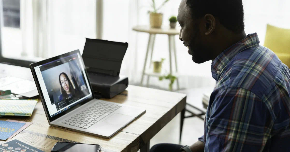 Man on a video call at a laptop on a home desk