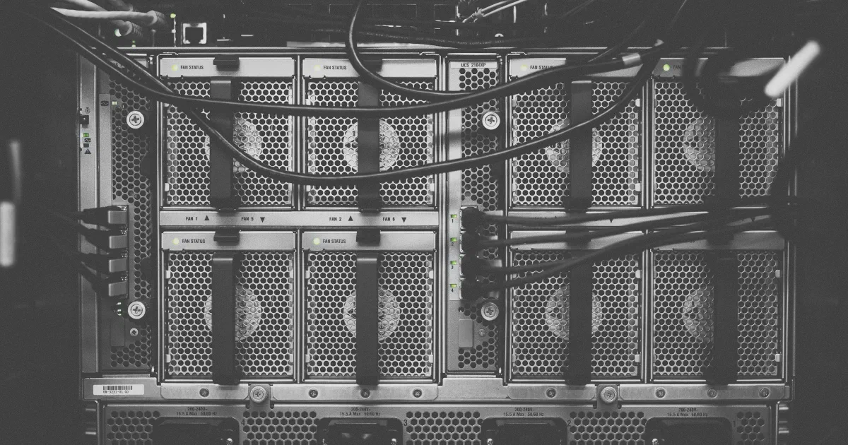 Black-and-white photo of the back of a network equipment chassis with fan modules and cables
