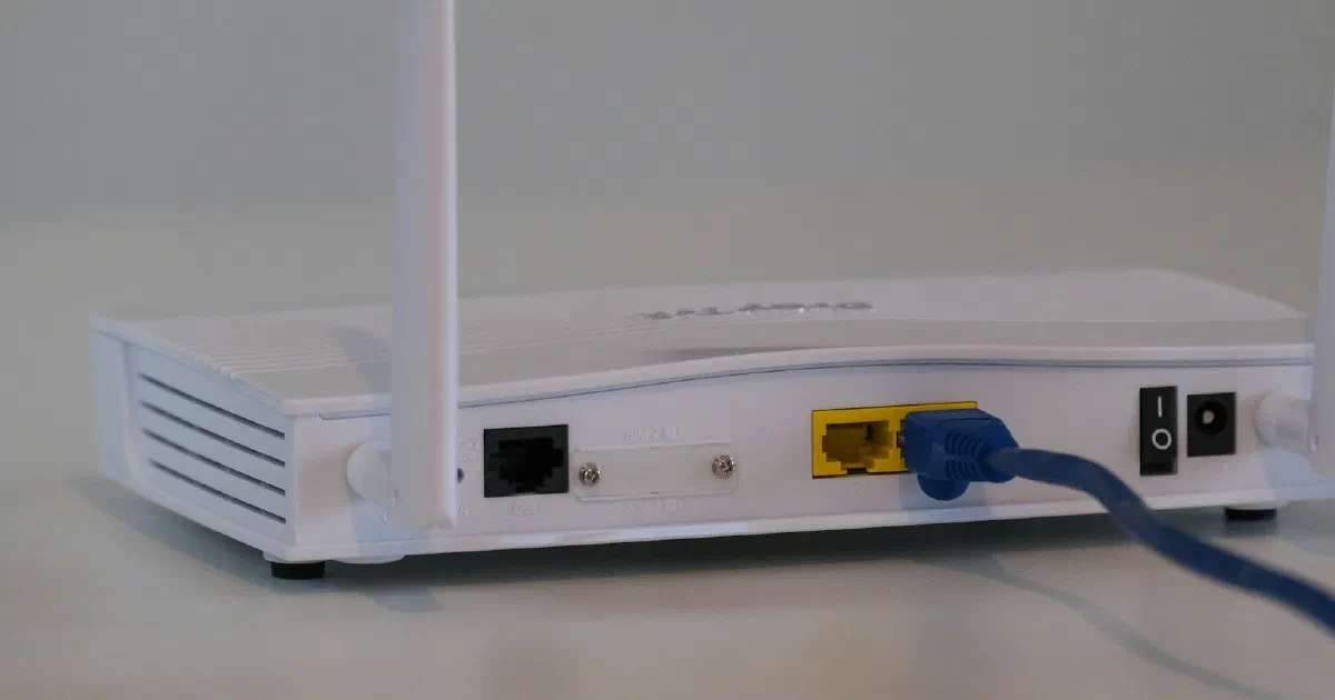 White Wi-Fi router with a blue Ethernet cable plugged into the back