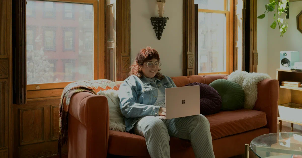 Person sitting on a couch at home working on a laptop