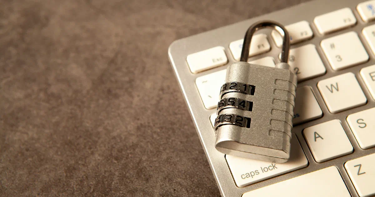 Silver combination padlock resting on a white computer keyboard