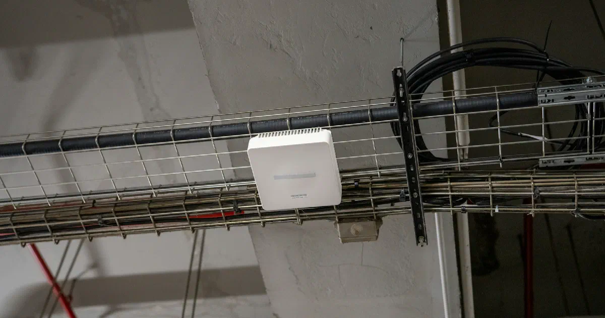 White Wi-Fi access point mounted on a metal cable tray