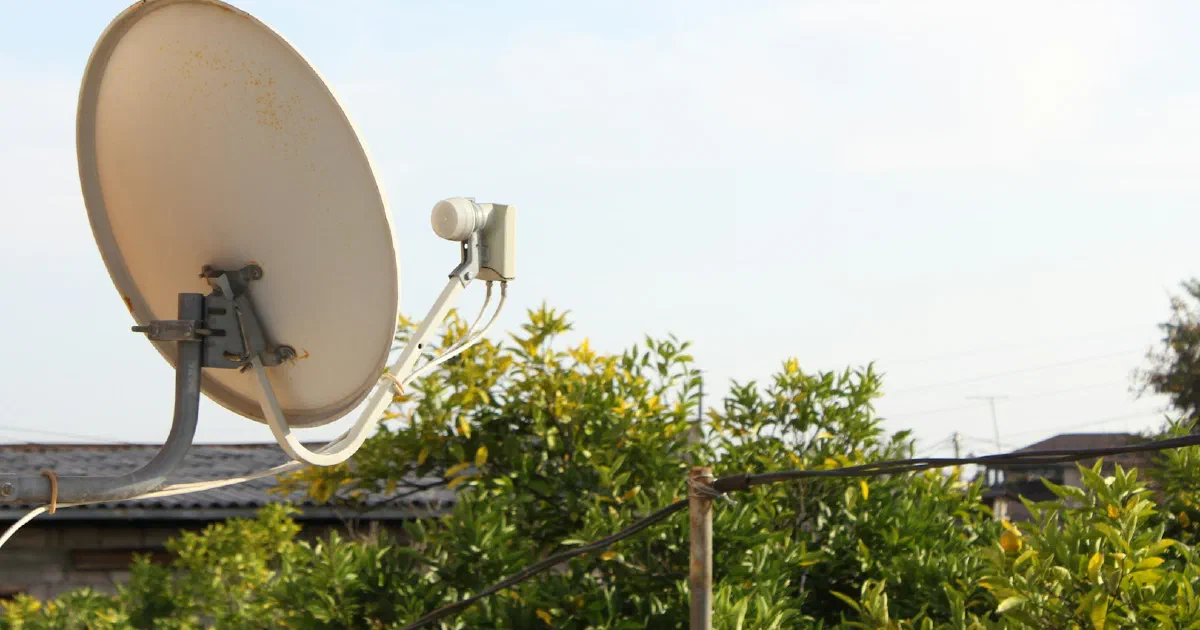 Satellite dish mounted on the side of a building against the sky