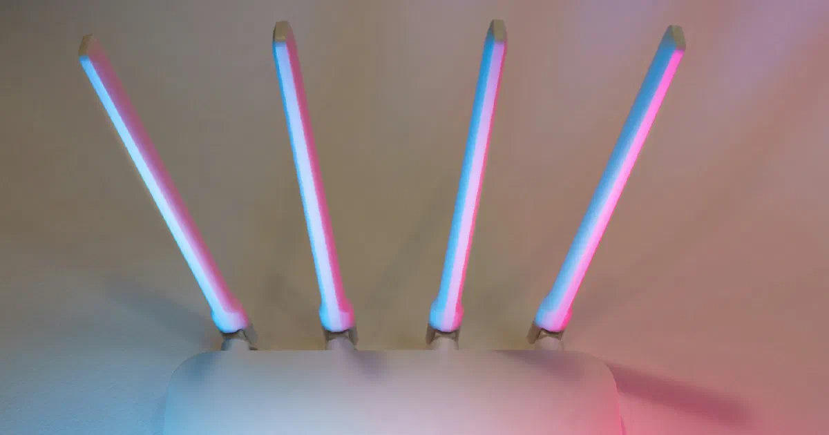 White Wi-Fi router with four antennas lit in blue and pink light
